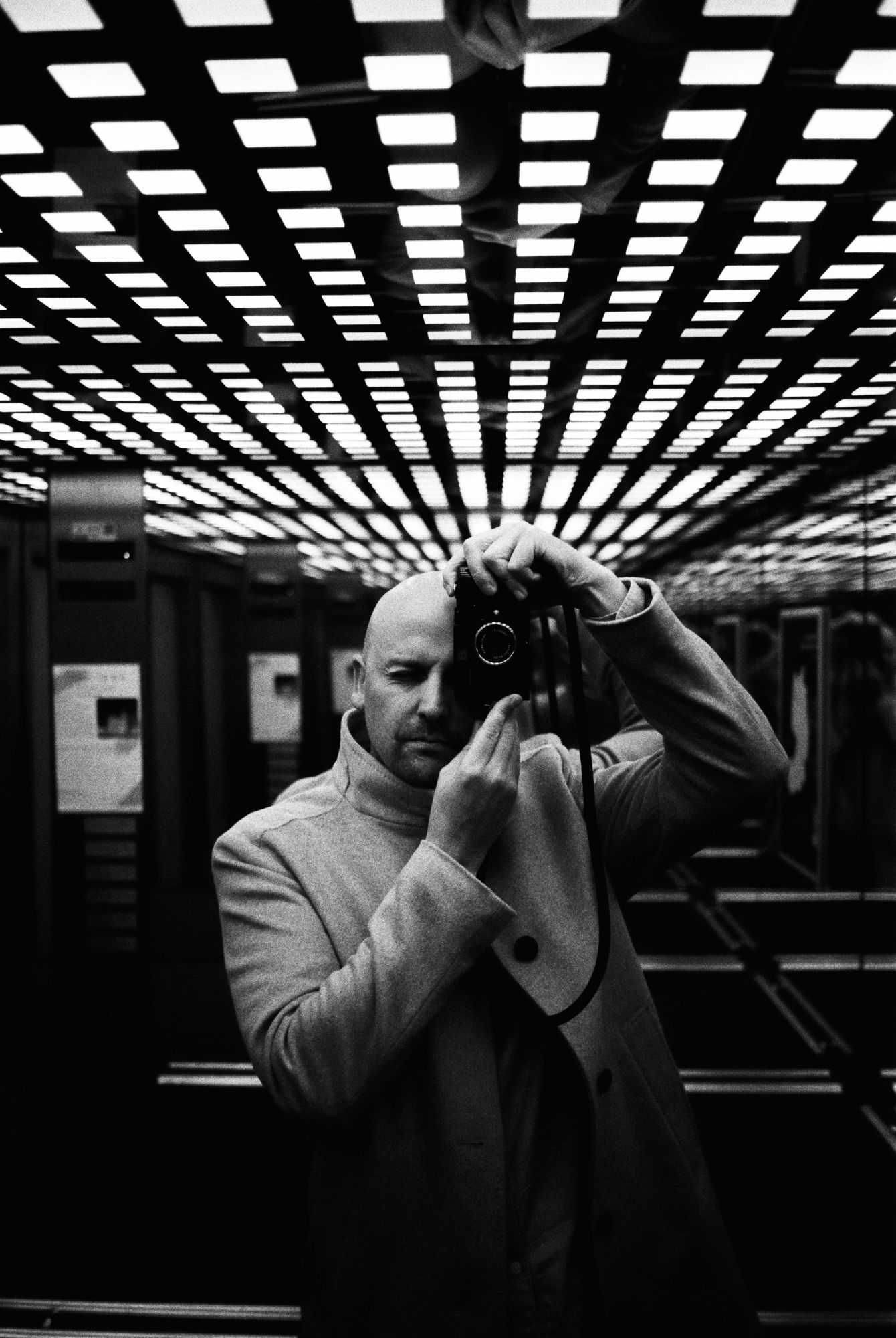 Self-portrait with Leica in elevator, black and white